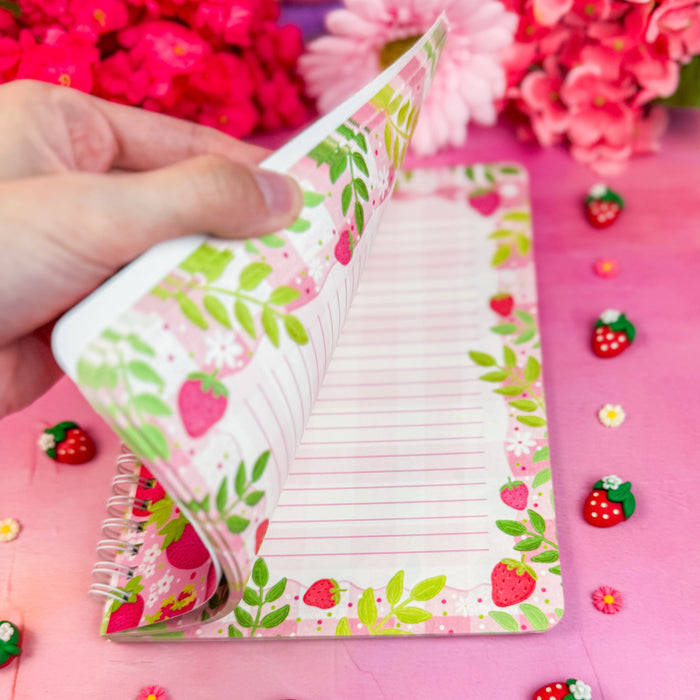 Interior of notebook with strawberry design on a pink background with decorative elements