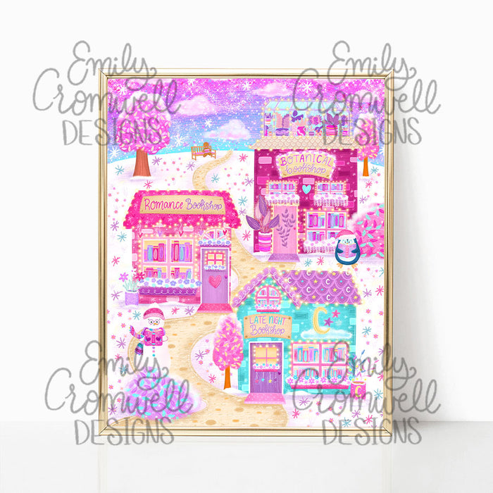 An art print with an illustration of three bookstores, along a snowy path, purple and pink stars, and a purple and pink sky. The art print is in a shiny gold frame against a white background.