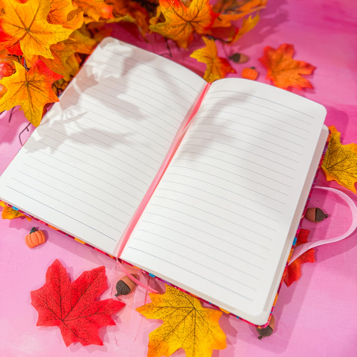 A college ruled lined journal opened with fall leaves in the background.