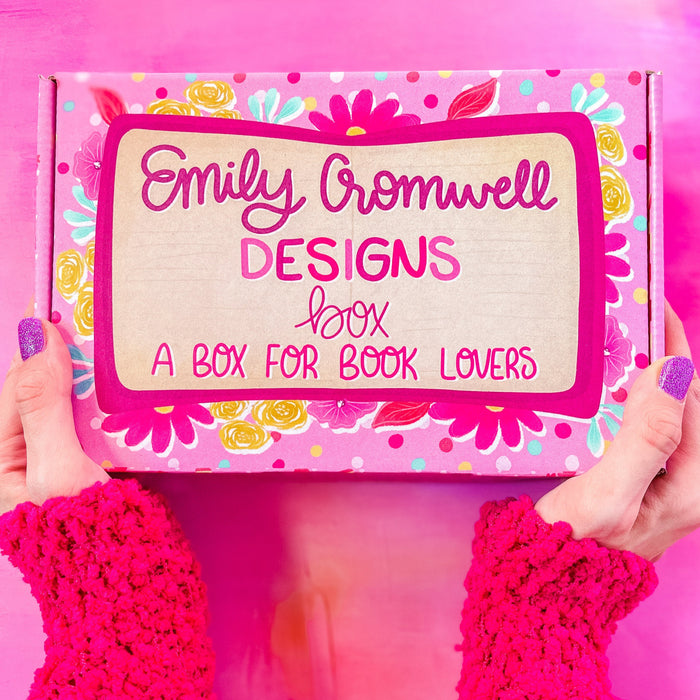 A person holding a colorful box with 'Emily Cromwell Designs' branding and text 'A BOX FOR BOOK LOVERS' on the lid.