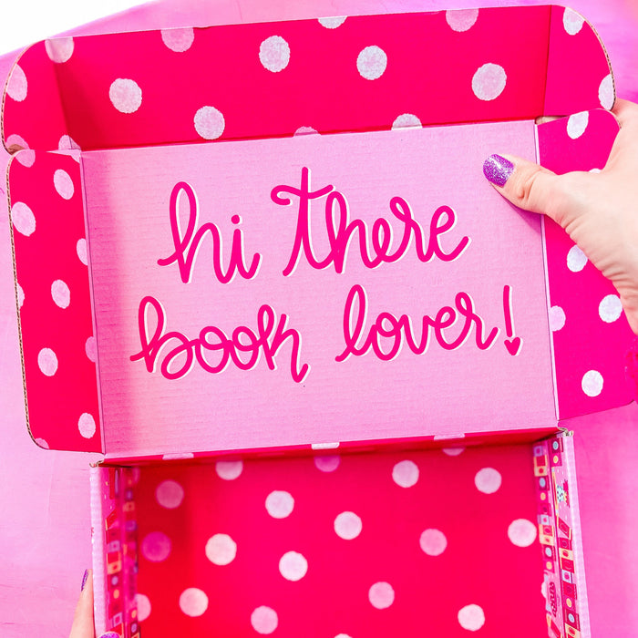 A pink subscription box with "hi there book lover!" text on the inside.