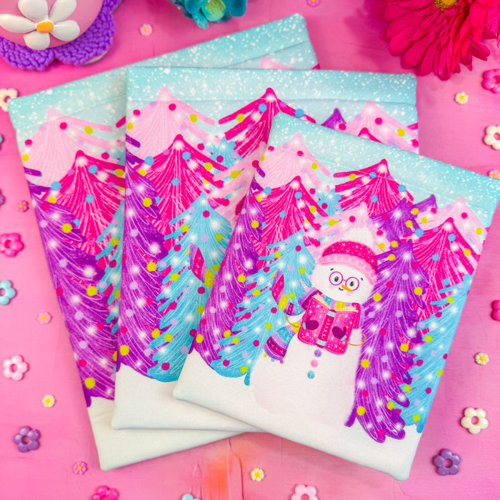 A stack of three winter snowman book sleeves on a bright pink background.