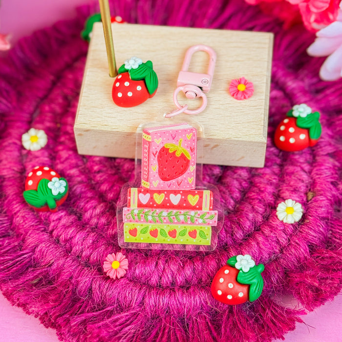 Wooden stand with strawberry-themed keychain on a pink floral background