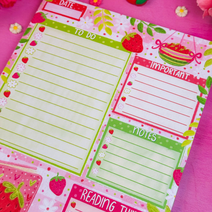 Notepad with strawberry-themed sections on a pink background