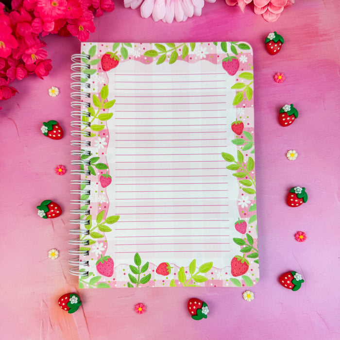 Notebook interior with floral and strawberry design on a pink background with flowers and candies.