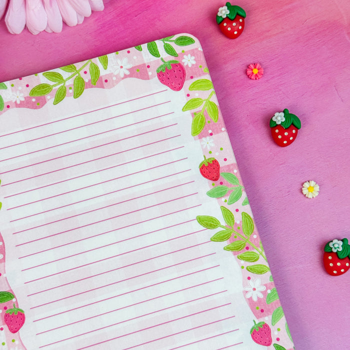 Notebook interior with strawberry and flower design on a pink surface with flowers and decorative stickers.