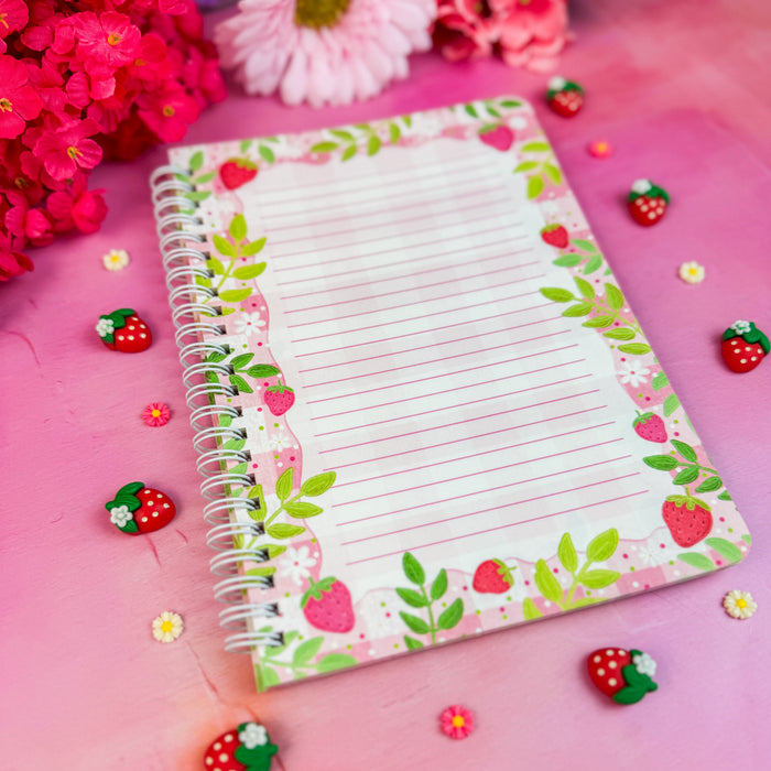 Notebook interior with strawberry design on a pink background with flowers and decorative items.