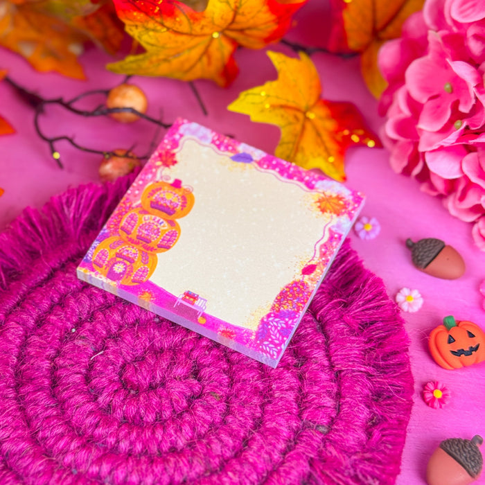 Detail shot of sticky notes with 3 stacked pumpkins and pink, yellow, and red leaves and glitter around the edges. Against a bright pink background.